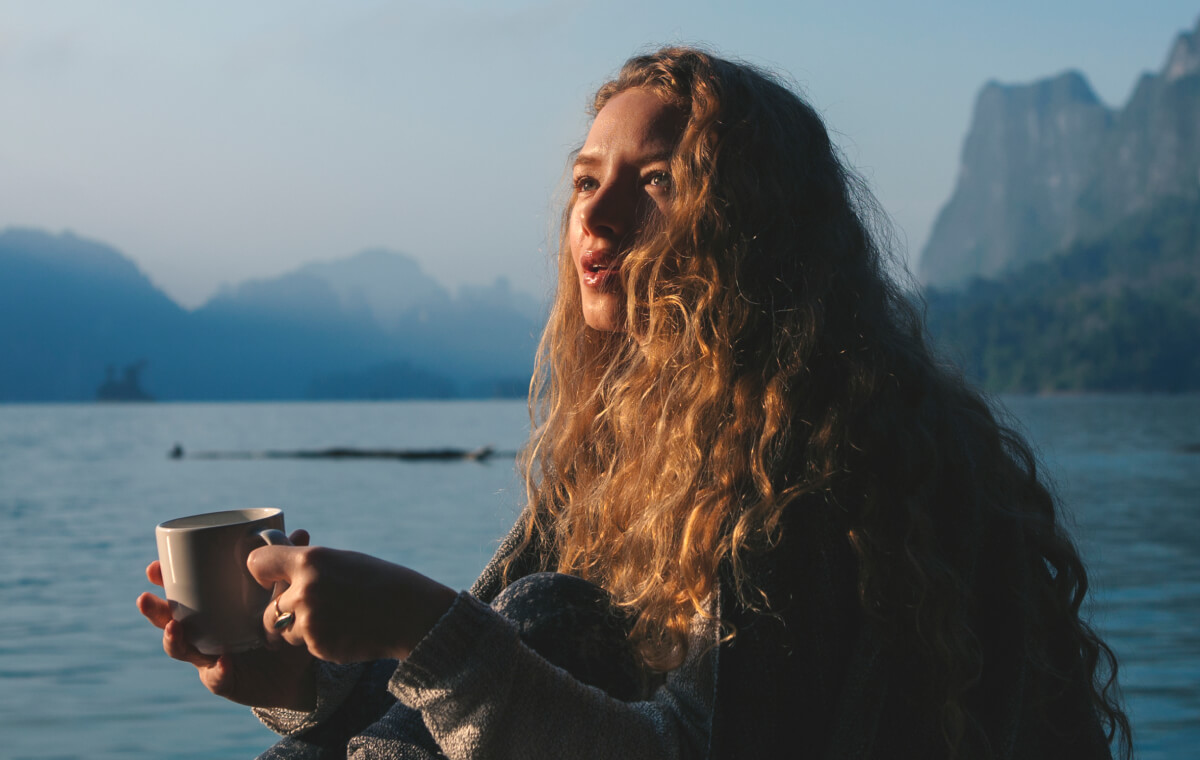 chica de pelo largo tomando café en naturaleza sol